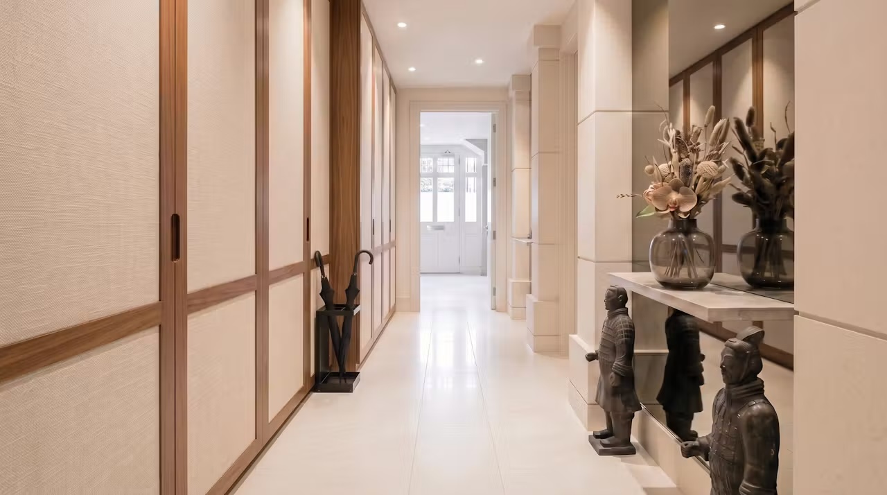 The finished hallway — mirrored panelling, brass details and warm timber flooring — Palace Court, London