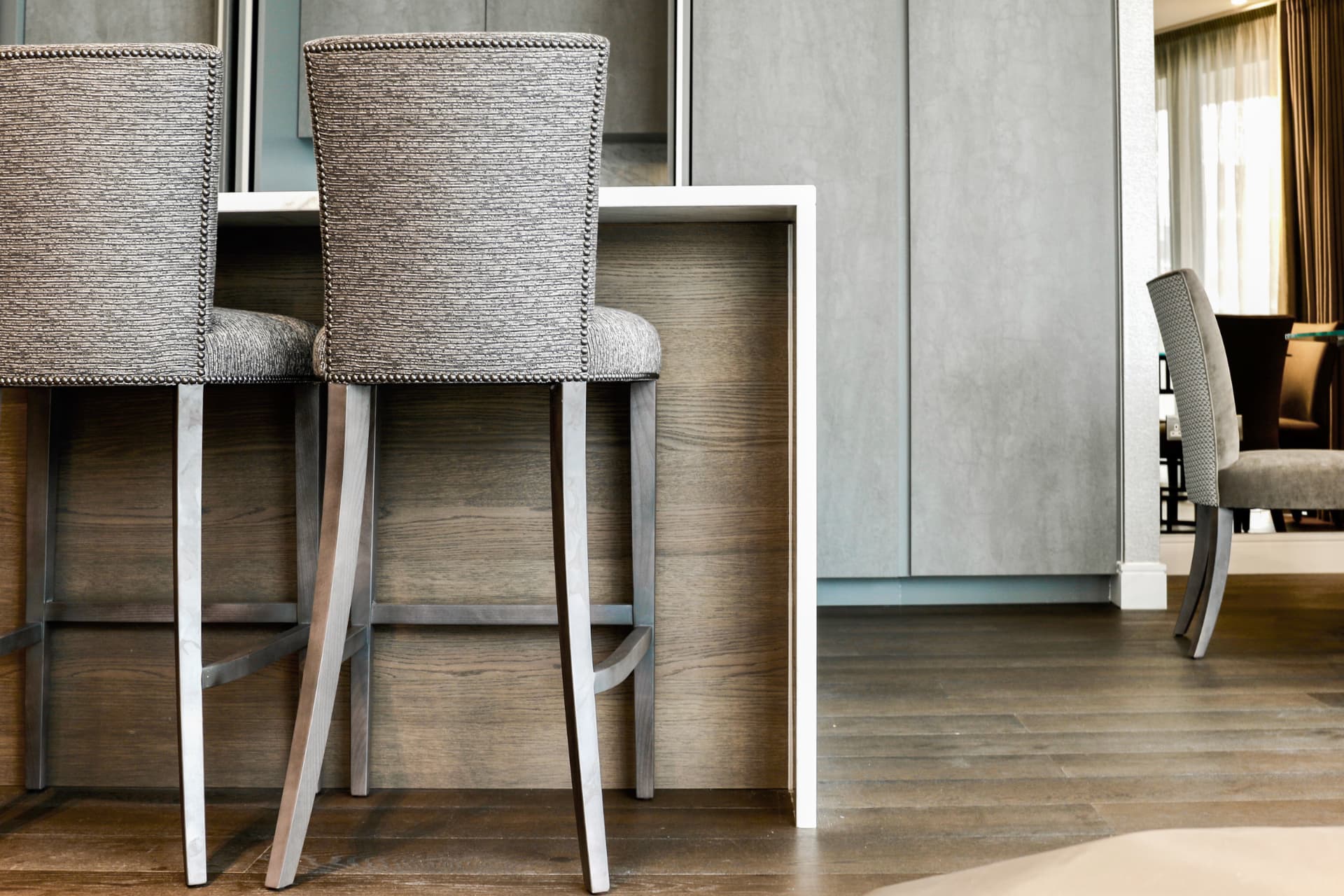 Furniture makers detail — bespoke bar stools with nailhead trim and hand-finished metal legs at a kitchen island